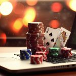 Fichas y cartas de casino encima de un ordenador portátil representando los juegos de casinos online